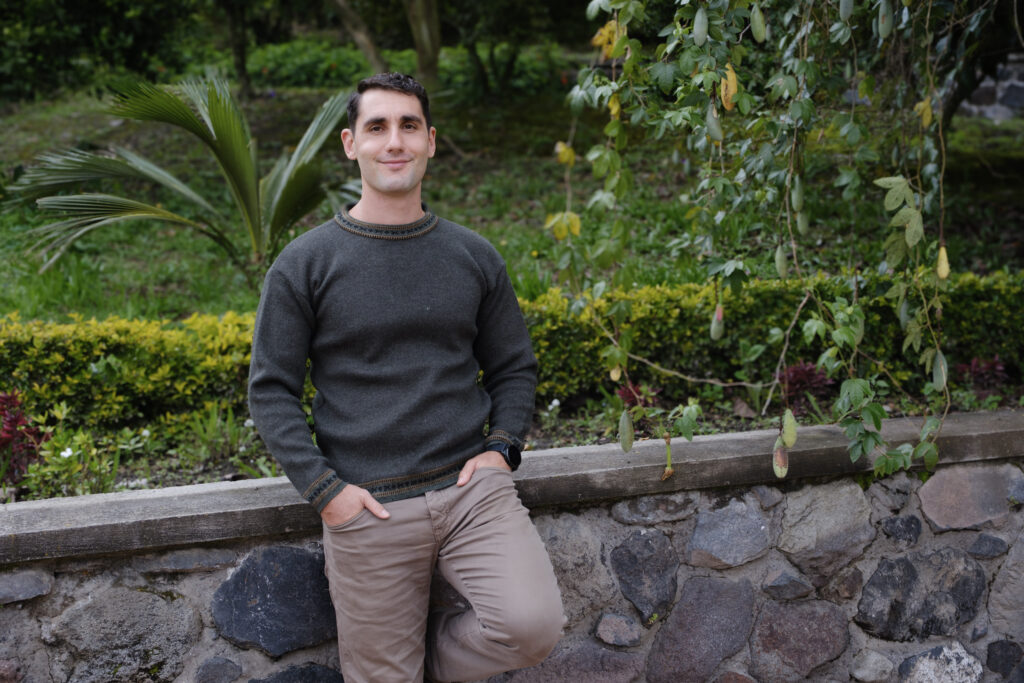 Simon Erlich, therapist in Ontario, leaning gently against a rock wall beside a vine, conveying care and compassion